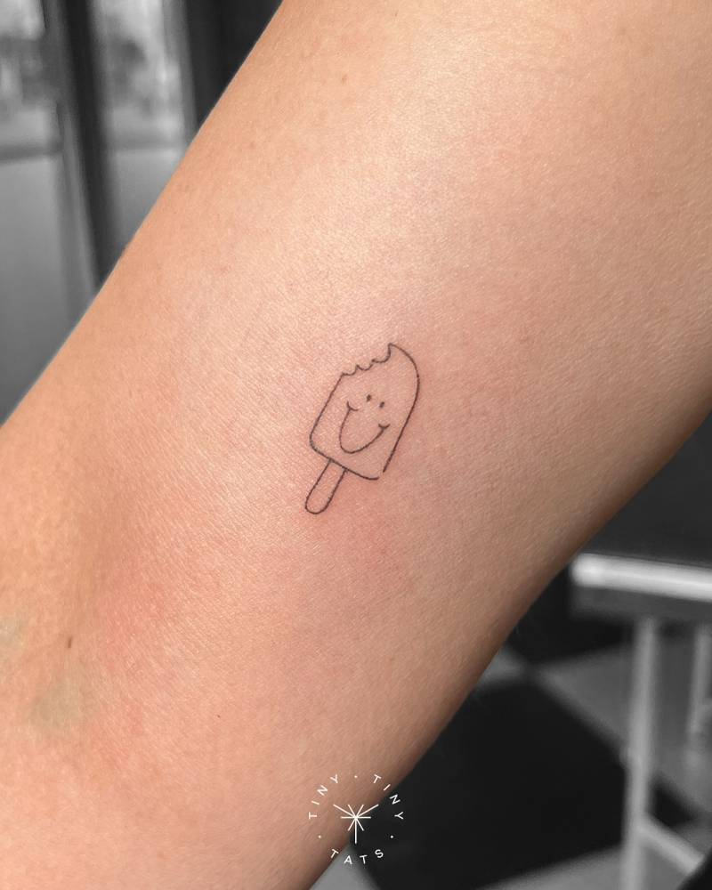Smiley ice lolly tattoo located on the inner arm.