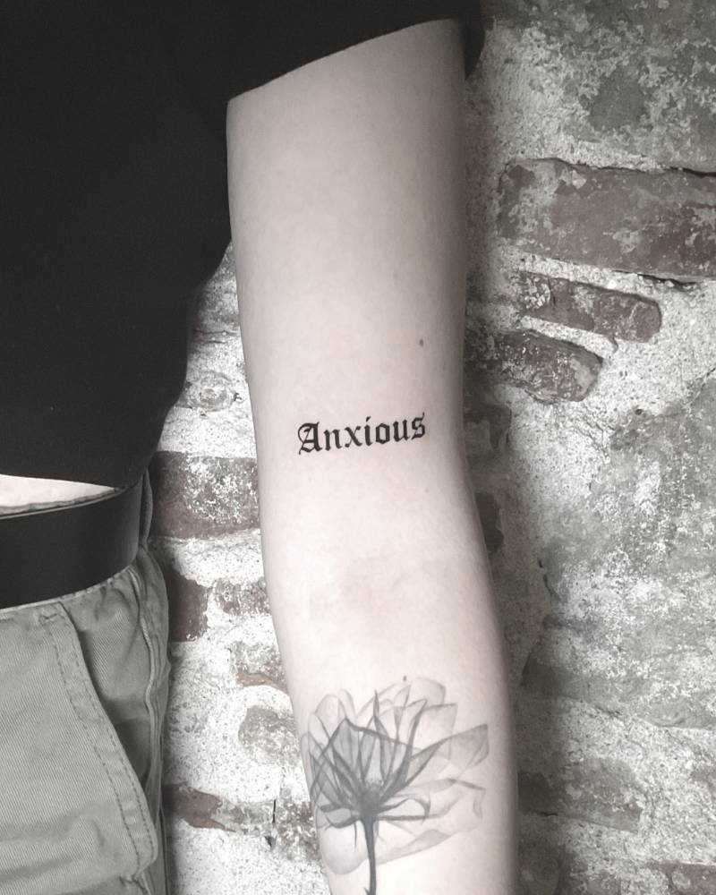 Lettering tattoo of the word "anxious" in gothic font.