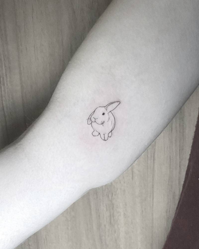 Cute little rabbit tattoo in fine line style located on the inner arm.
