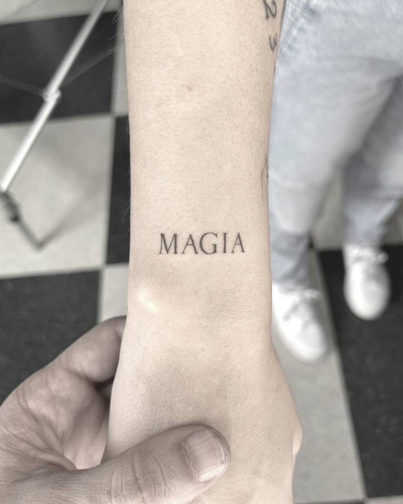 Lettering tattoo of the word "magia" in serif font.