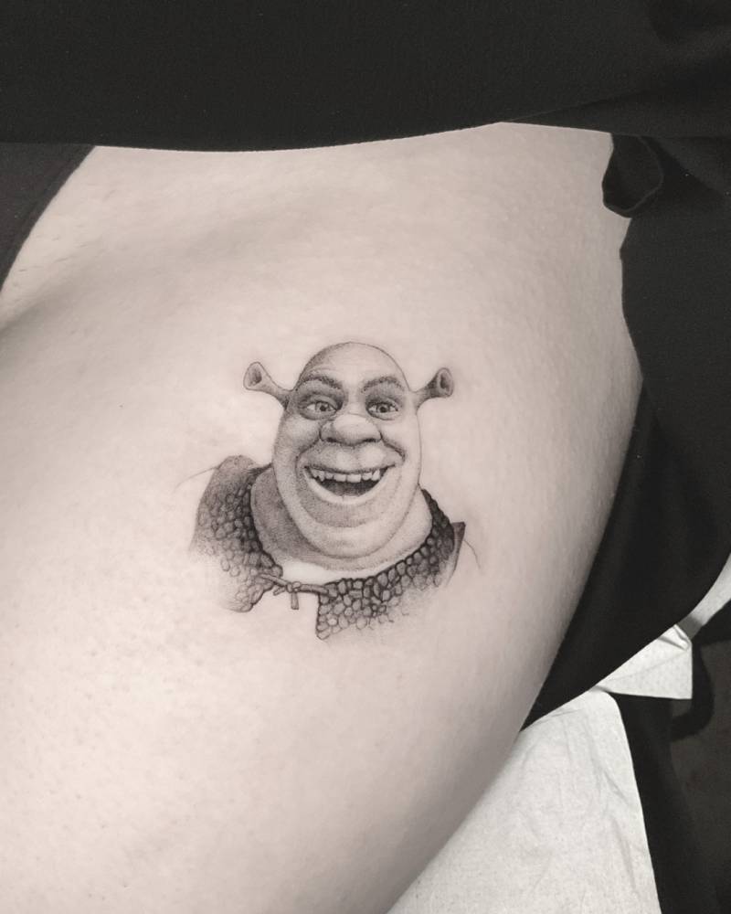 Shrek portrait tattoo located on the thigh.