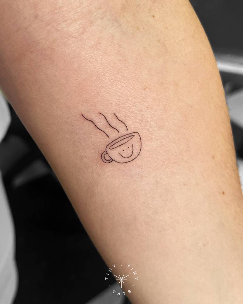 Smiley coffee cup tattoo located on the inner forearm.