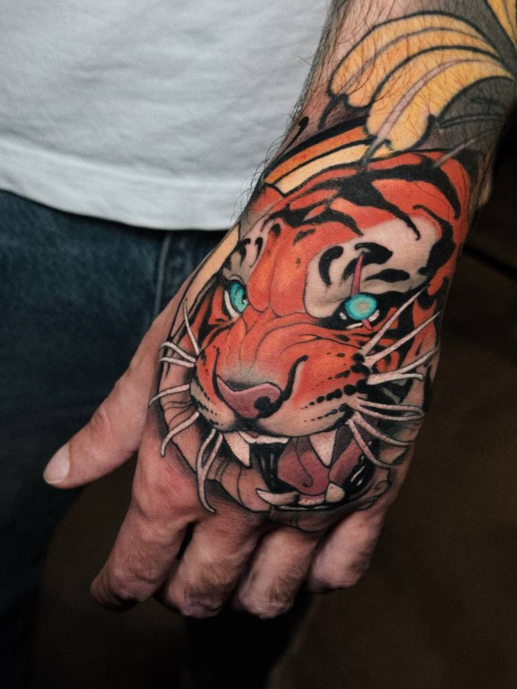 Neotraditional style tiger head tattoo located on the hand.