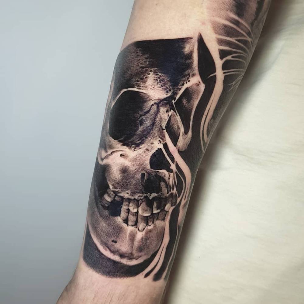 Black and grey skull tattoo located on the forearm.