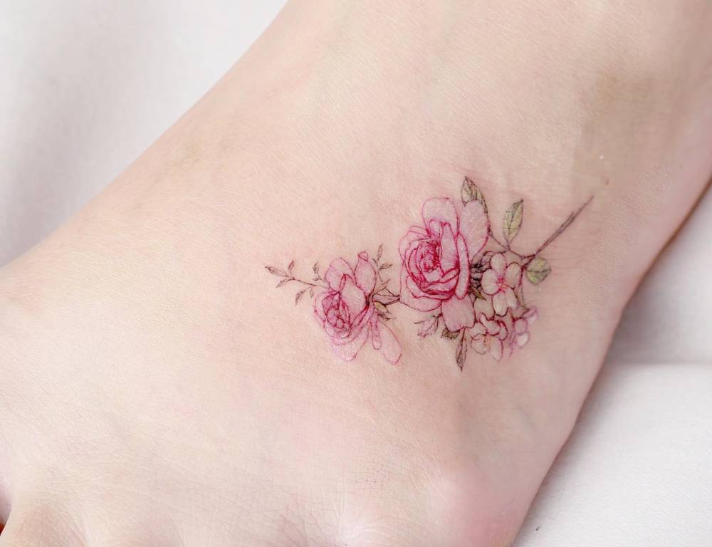Pink roses and cherry blossom tattoo located on the foot.