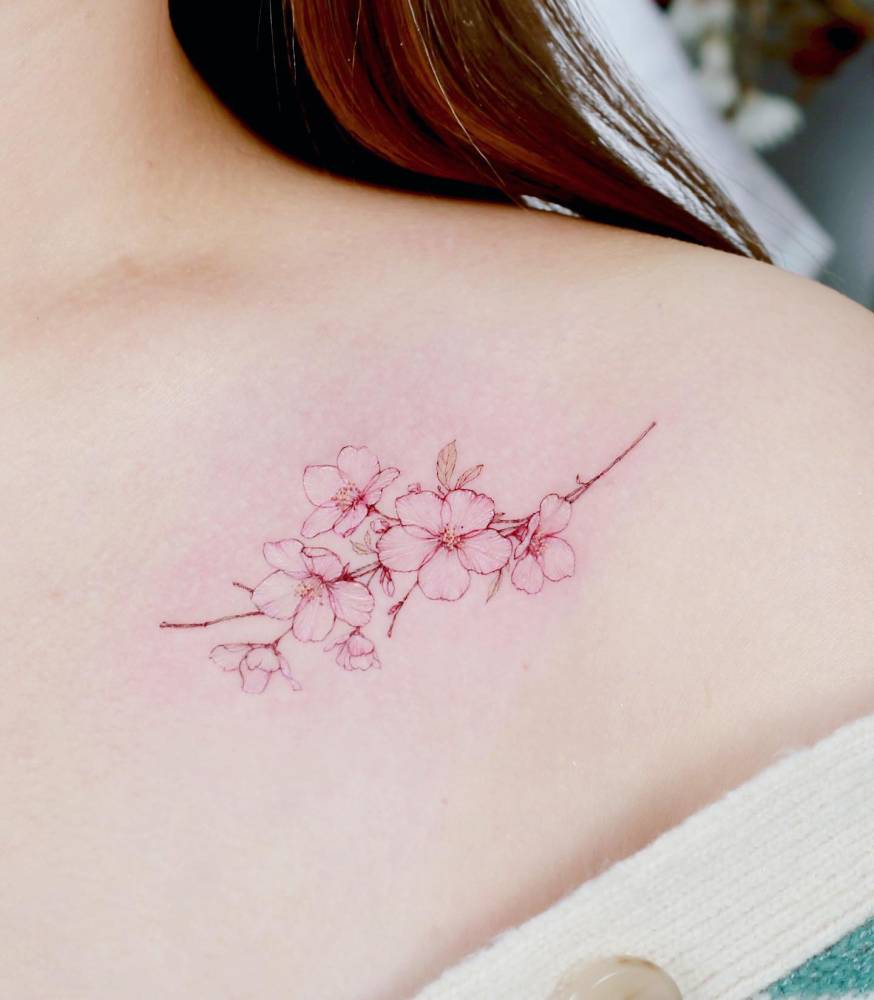Cherry blossom tattoo in watercolor style done on the collarbone.
