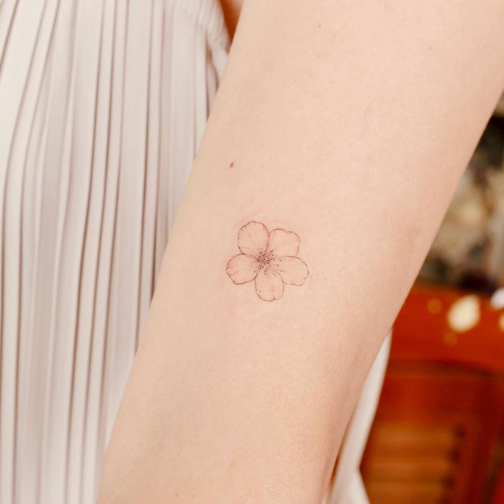 FIne line style cherry blossom tattoo located on the wrist.