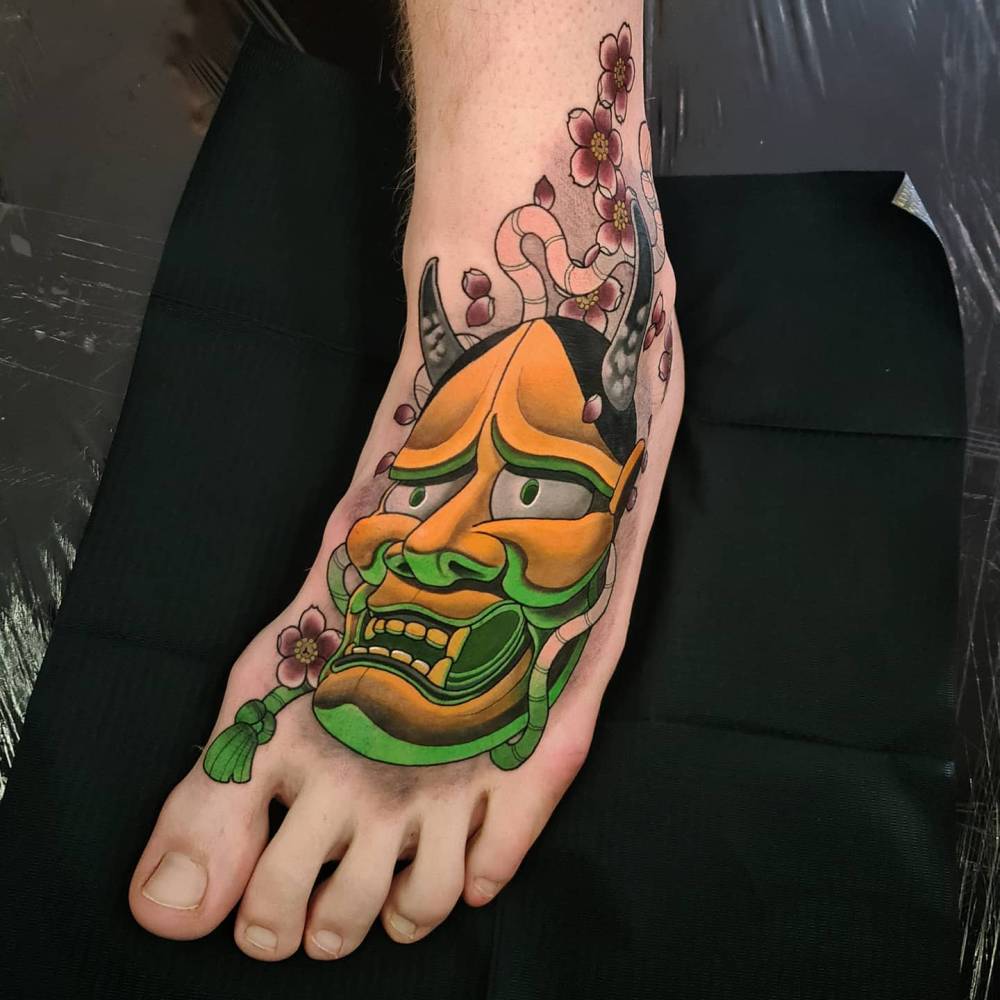 Neotraditional style hannah mask tattoo located on the foot.