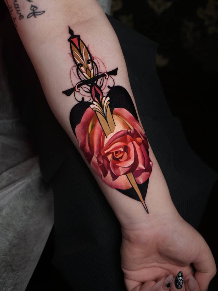 Rose and dagger tattoo in pop art style located on the inner forearm.