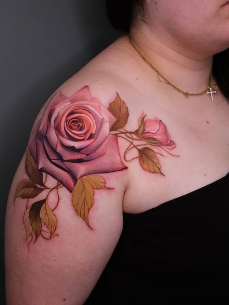 Pink rose head tattoo in realism located on the shoulder.