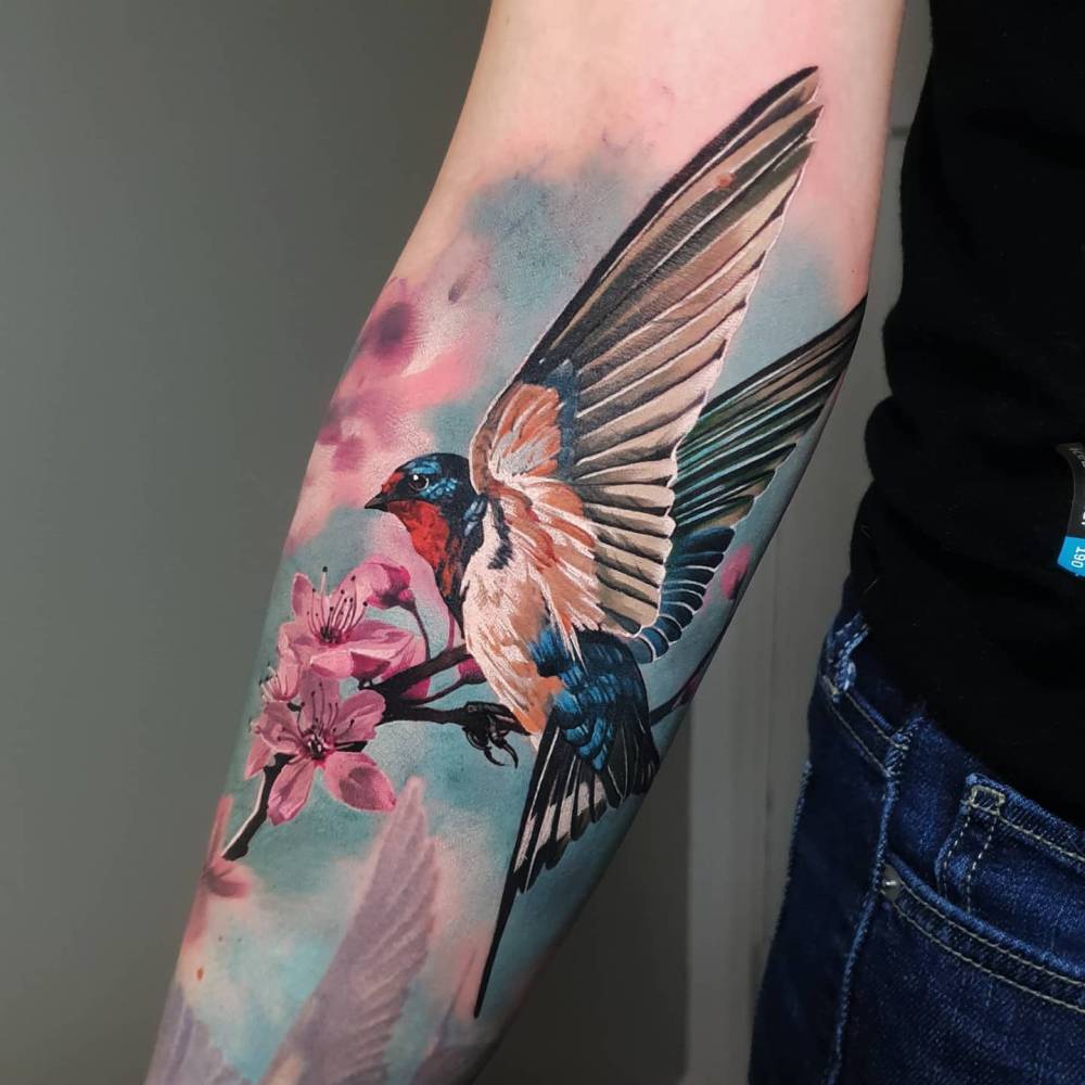 Swallow and cherry blossom tattoo located on the inner forearm, realistic style.