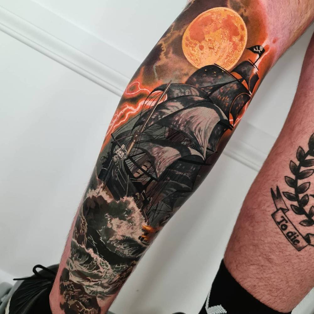 Sailing ship tattoo located on the shin, realistic style.