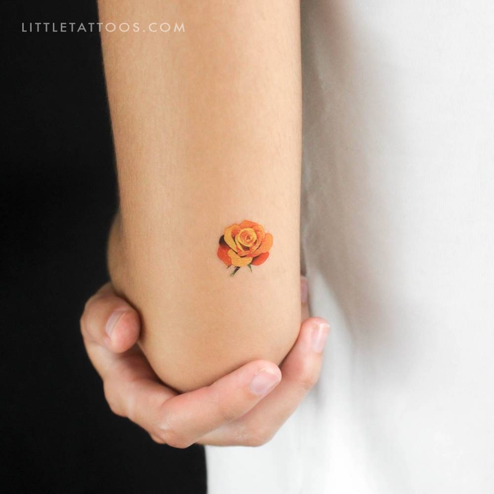 Watercolor style small orange rose head temporary tattoo.