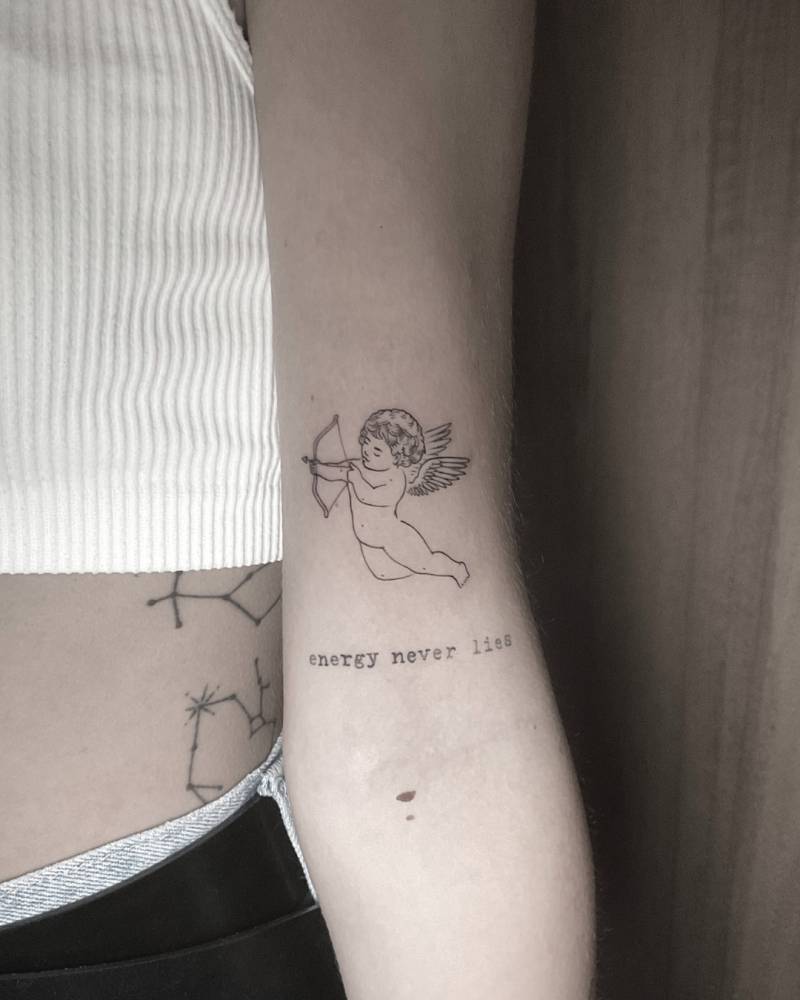 Cupid and "energy never lies" tattoo located on the bicep.