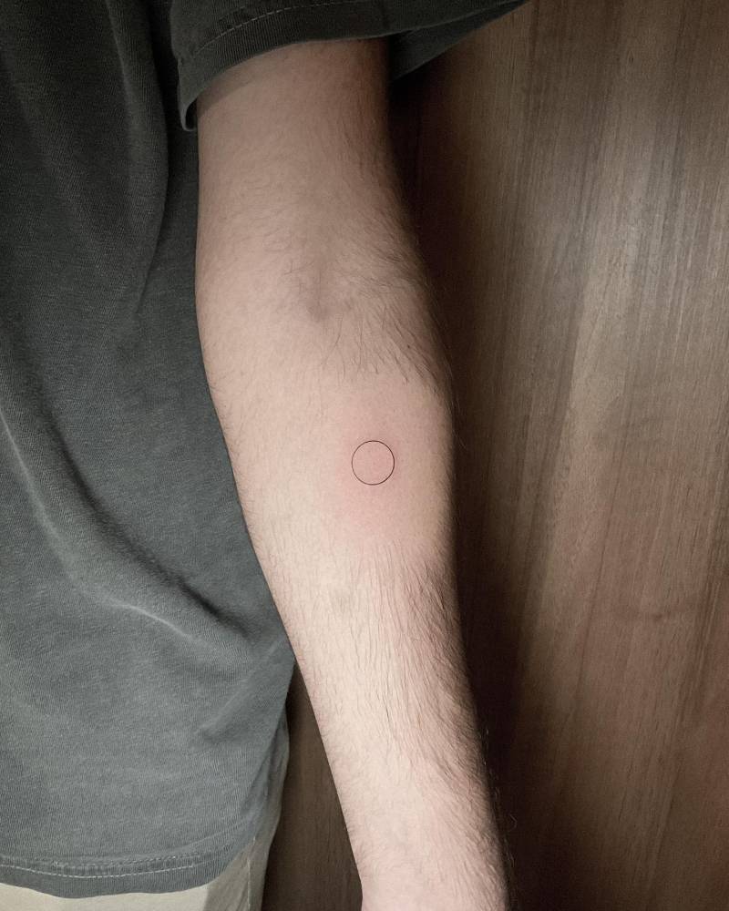 Minimalist style little circle tattoo located on the inner forearm.