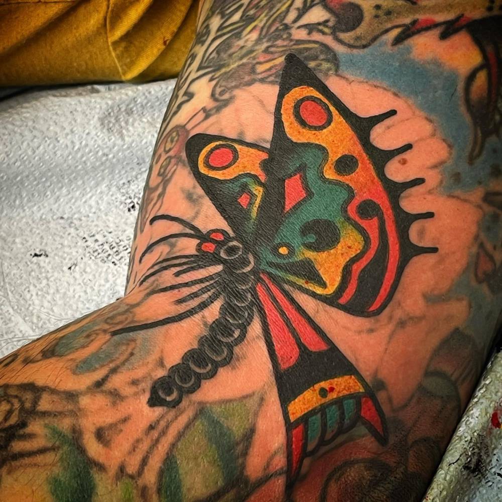Traditional style butterfly tattoo located on the elbow.