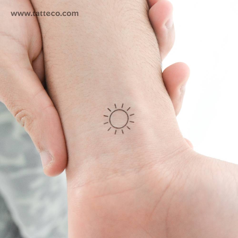 Minimalist sun temporary tattoo located on the wrist.