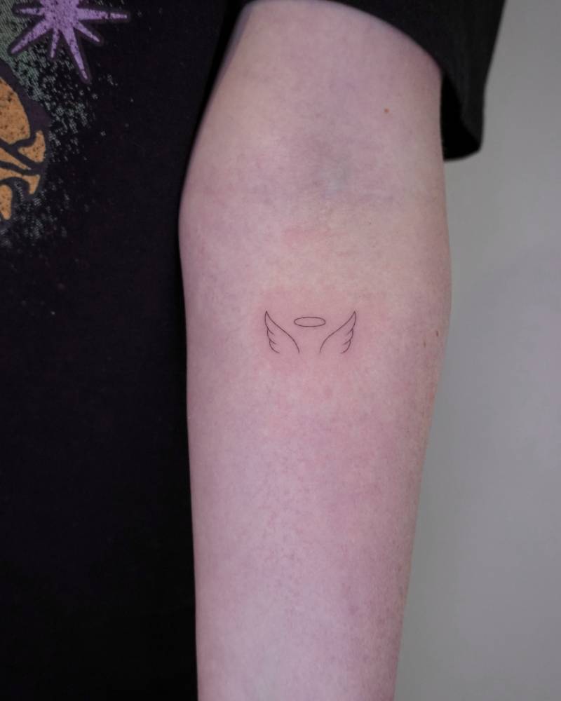 Angel wings and halo tattoo located on the inner forearm.