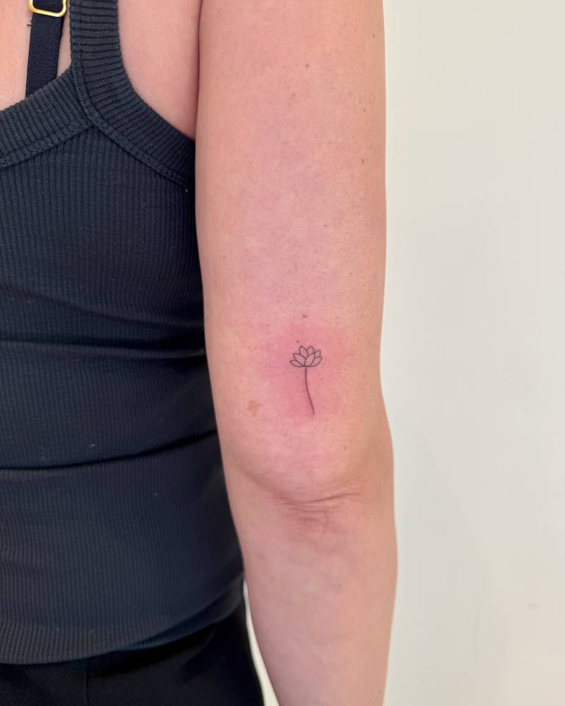 Minimalist lotus flower tattoo in fine line style.