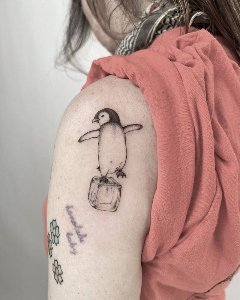 Penguin tattoo in illustrative style located on the upper arm.