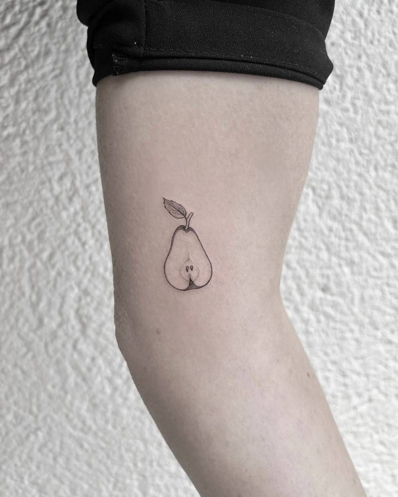 Tiny pear cut in half tattooed on the inner arm.