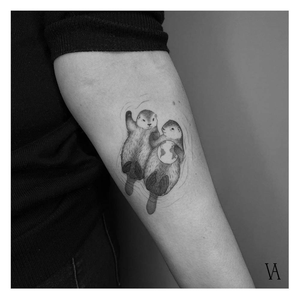 Otter couple tattoo located on the inner forearm, illustrative style.