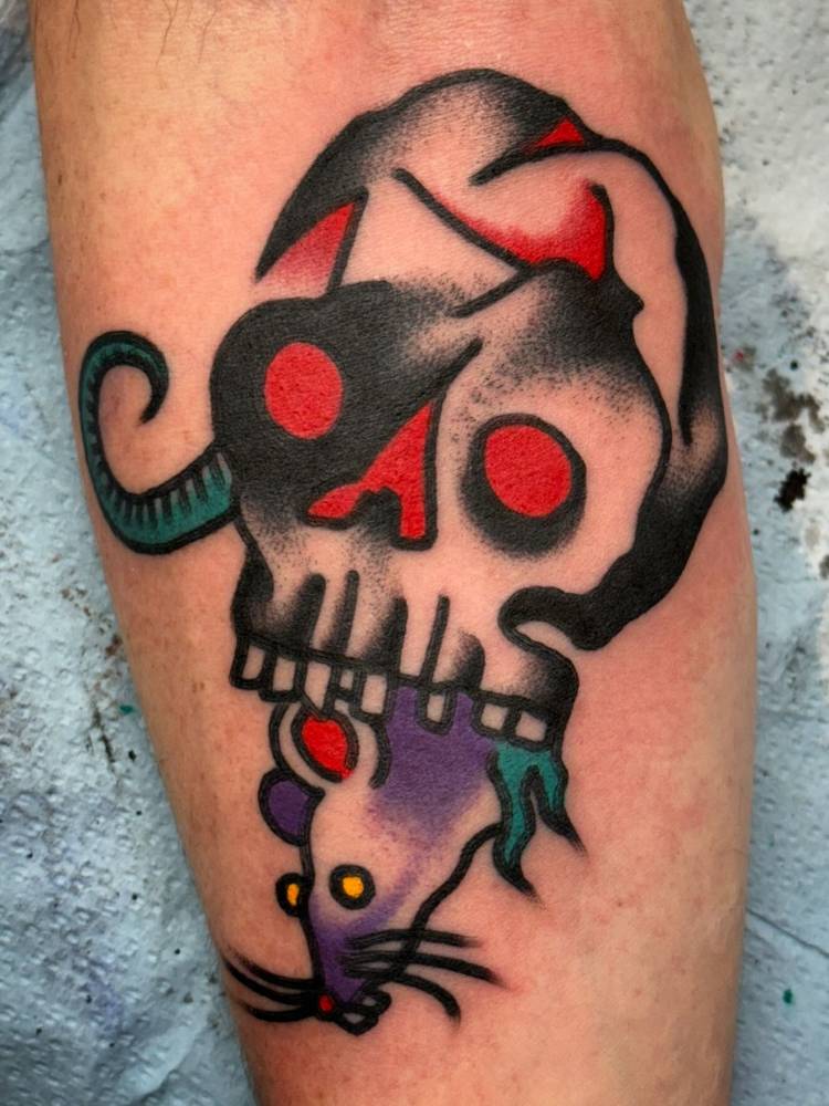 Skull and rat tattoo in traditional style located on the forearm.