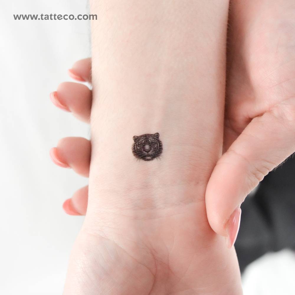 Tiny tiger portrait temporary tattoo located on the wrist.