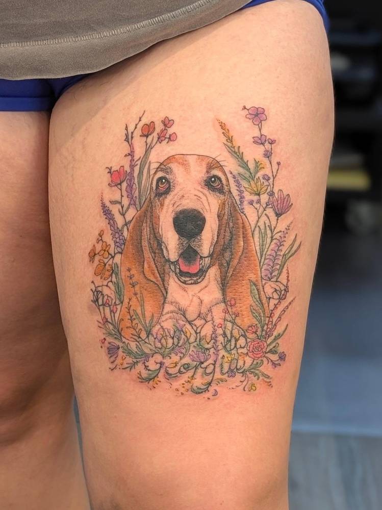 Basset Hound portrait tattoo located on the thigh, illustrative style.
