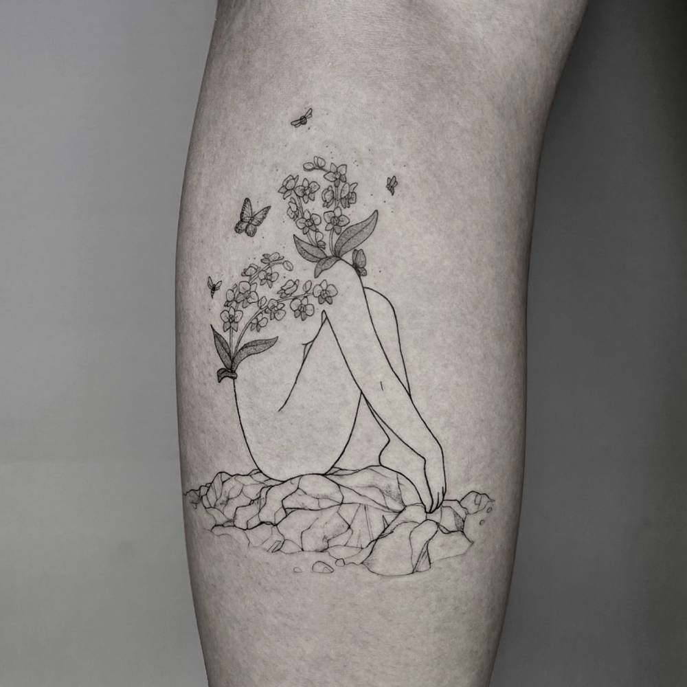 Flower head woman tattoo located on the inner arm.