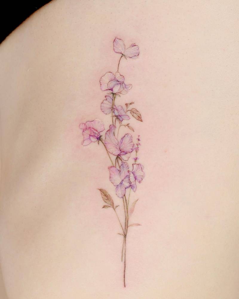 Sweet pea flowers in watercolor style tattooed on the rib.