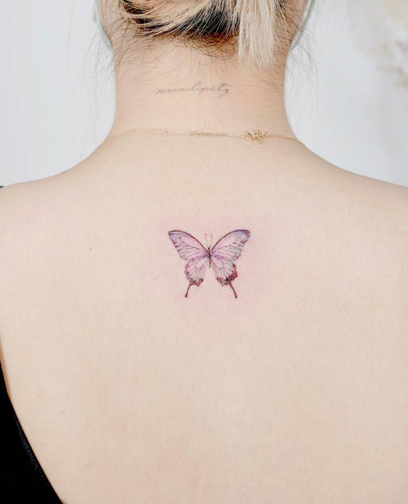 Purple butterfly tattoo located on the upper back, watercolor style.