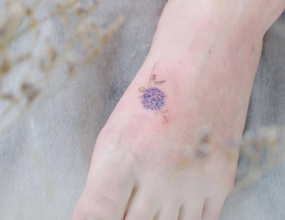 Hydrangea flower tattoo located on the foot, done in watercolor style.