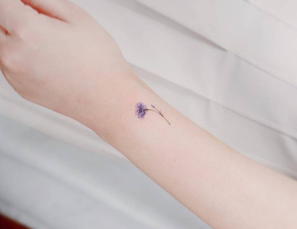 Little cornflower tattoo in watercolor style done on the wrist.