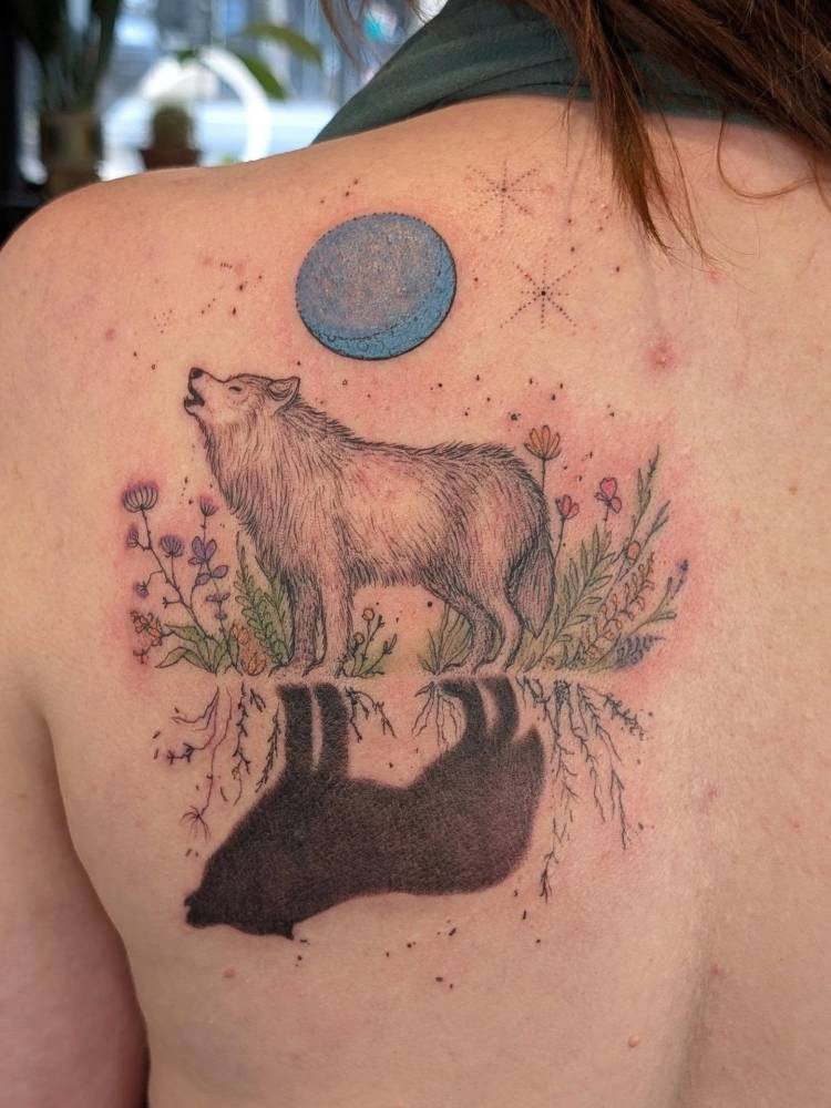 Wolf tattoo located on the shoulder blade, done in illustrative style.