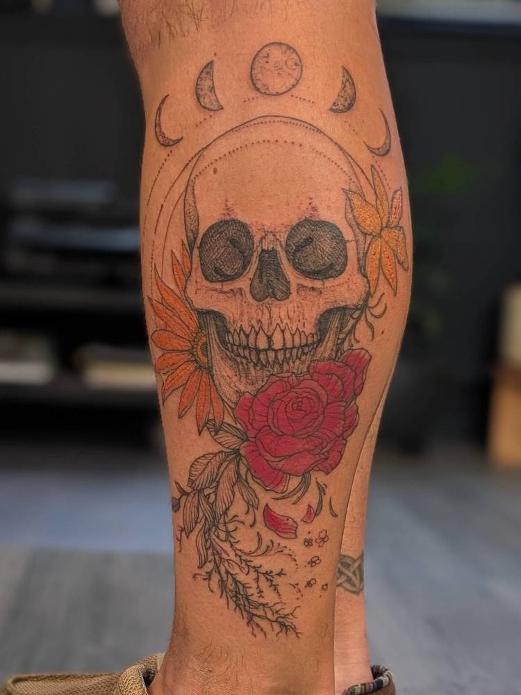Skull and red rose tattoo located on the shin.