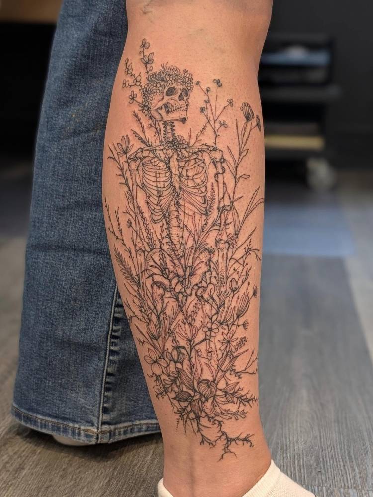 Skeleton and flowers tattoo in illustrative style located on the shin.