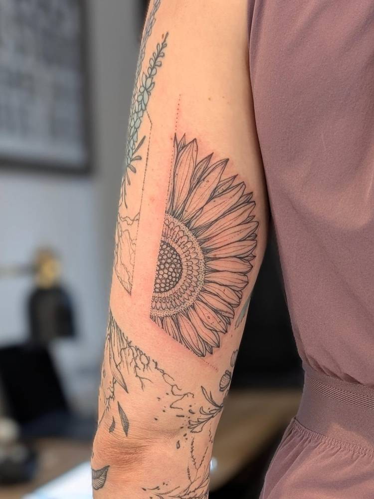Sunflower tattoo in illustrative style located ln the tricep.