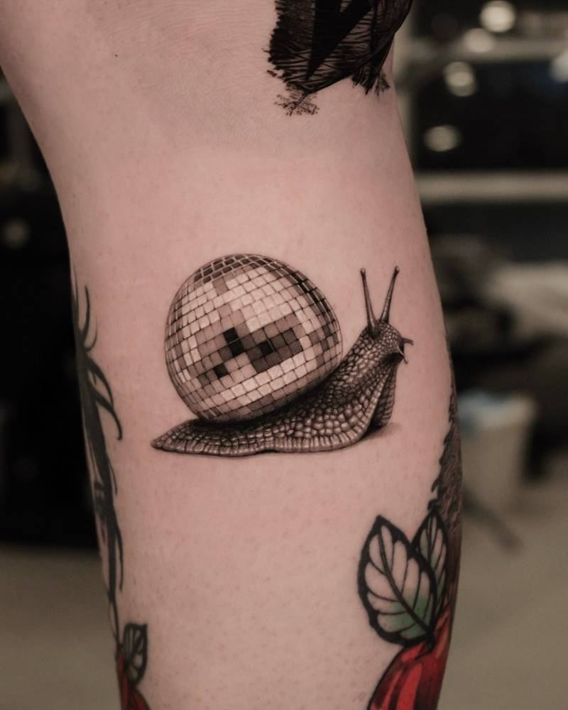 Disco snail tattoo located on the calf, micro-realistic style.