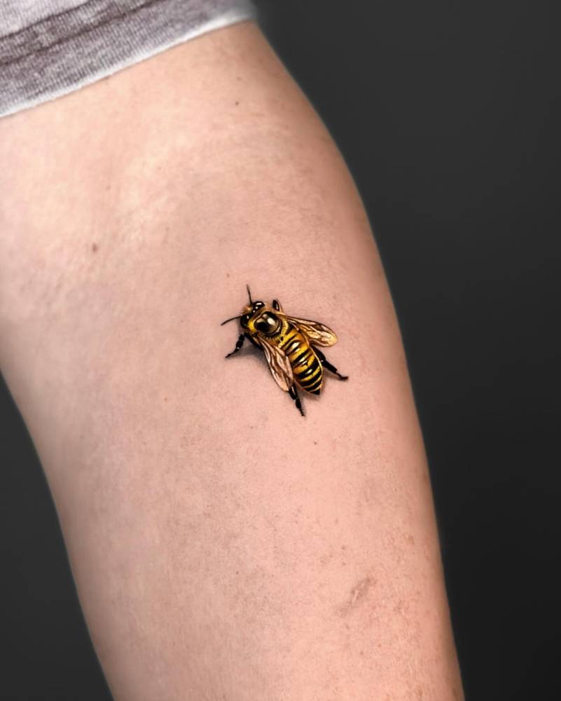 Micro-realistic style bee tattoo located on the inner forearm.