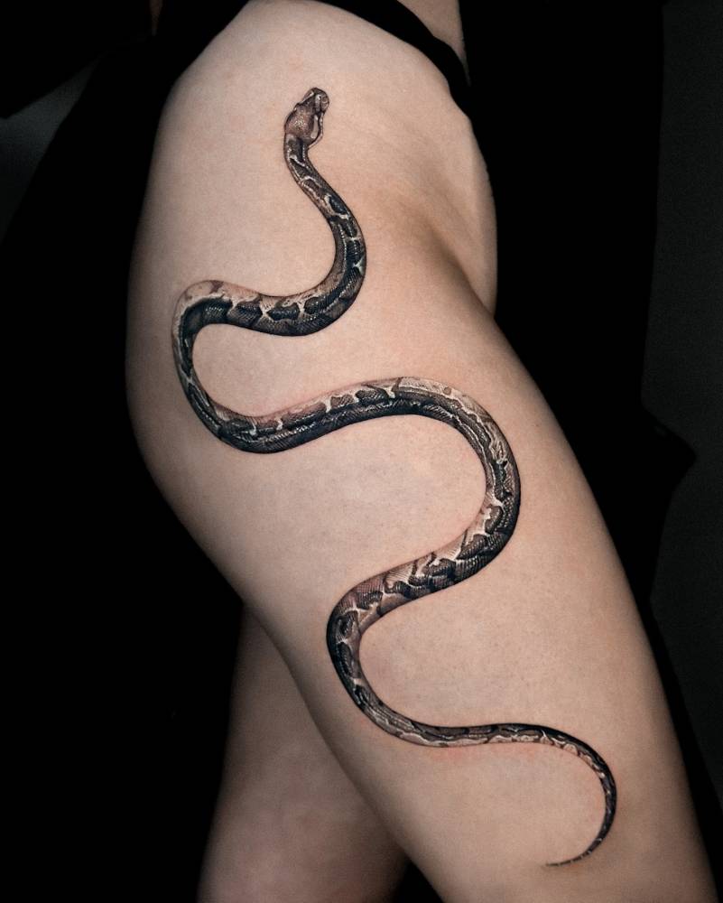 Snake tattoo in black and grey style located on the thigh.