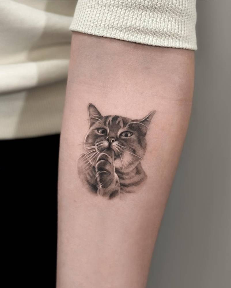 Cat portrait tattoo in micro-realistic style located on the inner forearm.