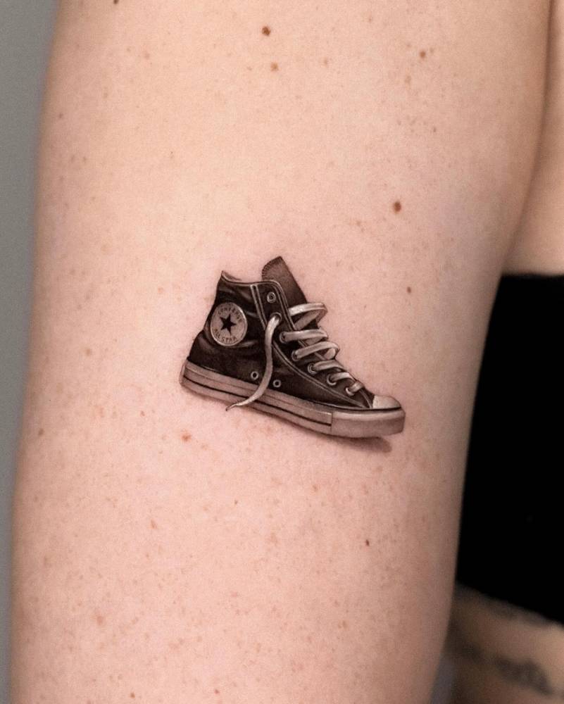 1.5 inch converse shoe tattooed on the upper arm.