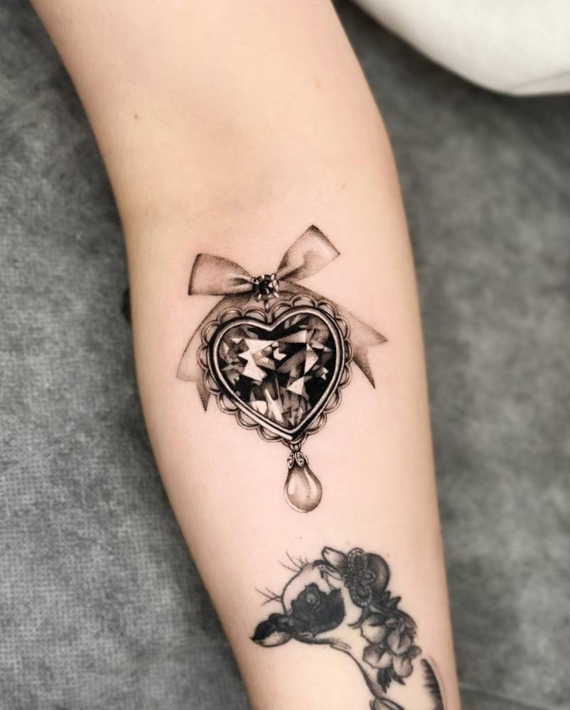 Black pendant tattoo located on the inner forearm.