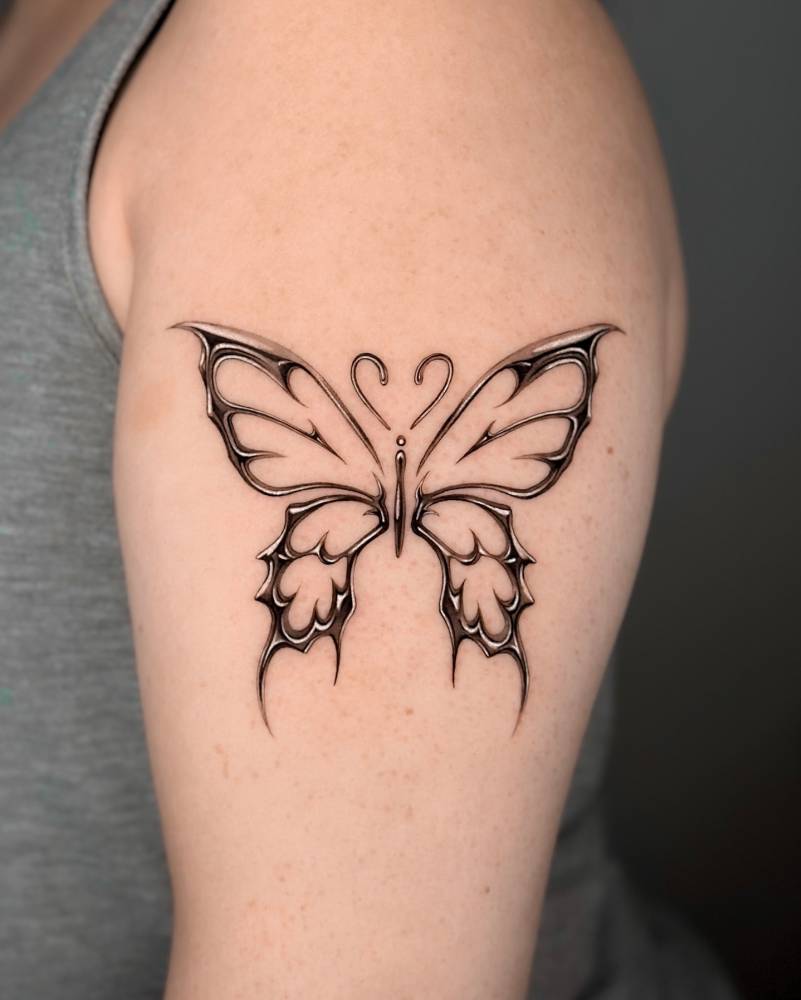 Chrome tribal butterfly tattoo located on the upper arm.