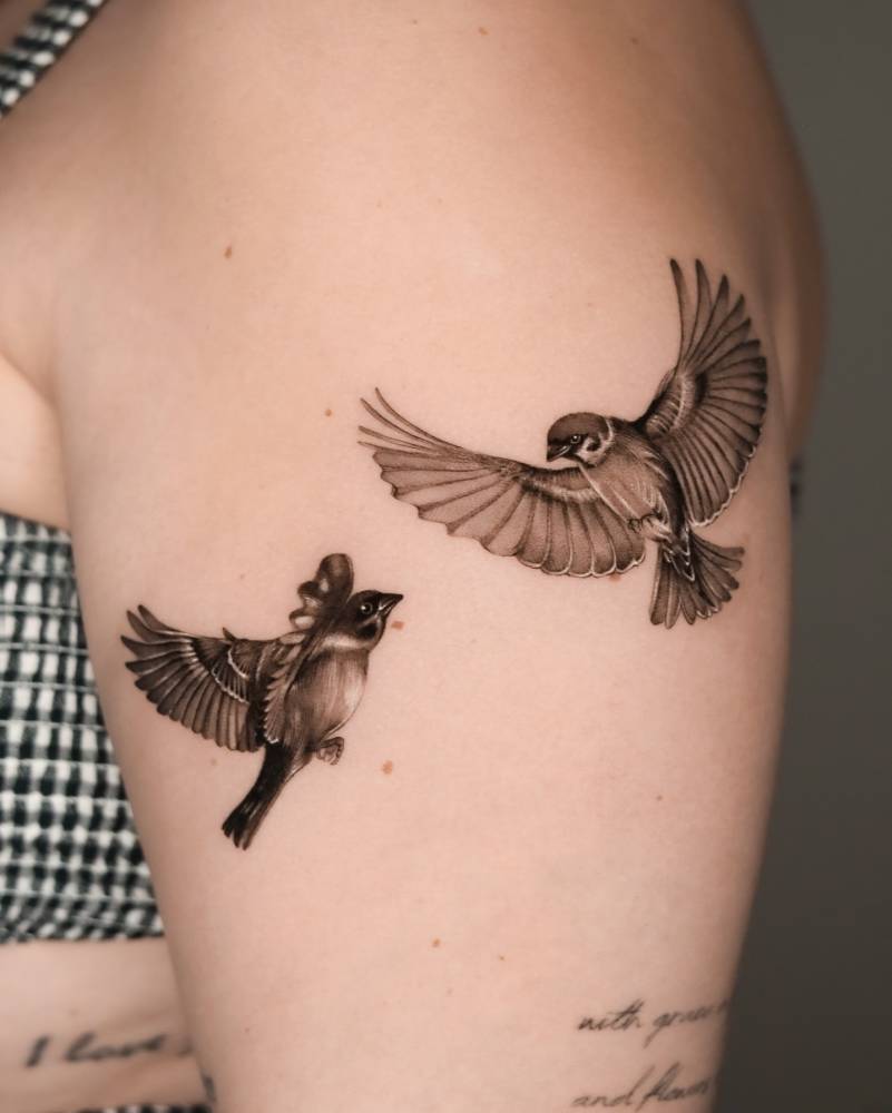 Sparrow couple tattoo located on the upper arm.