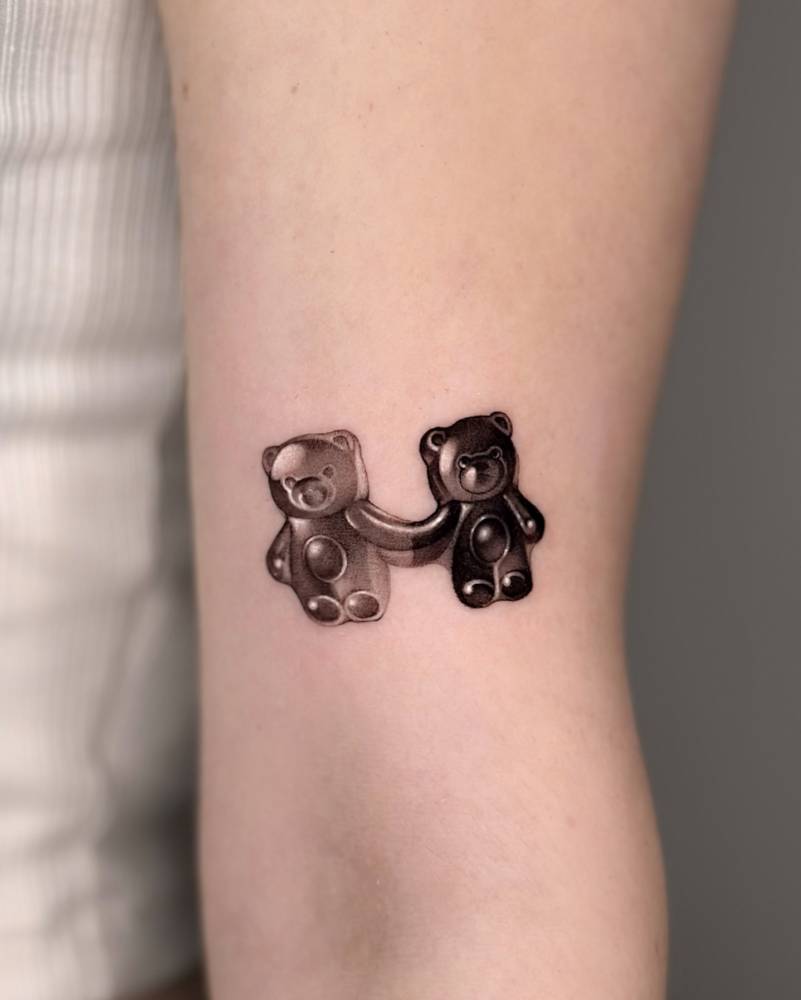 Gummy bears tattoo located on the bicep, micro-realistic style.