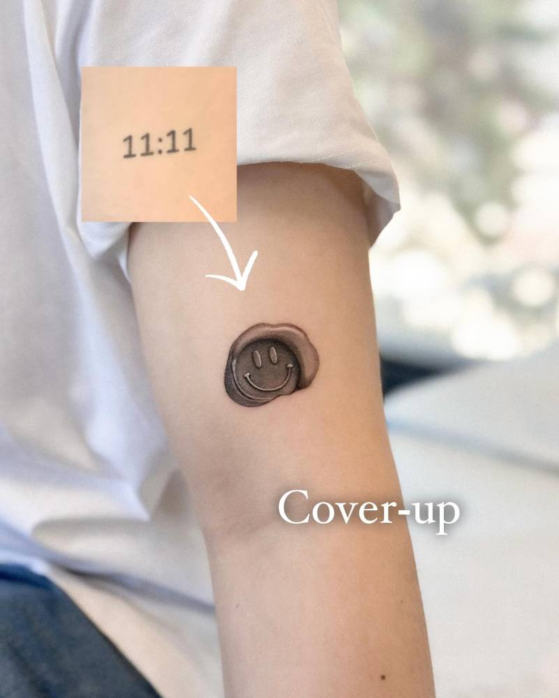 Smiley wax seal cover up tattoo done on the upper arm.