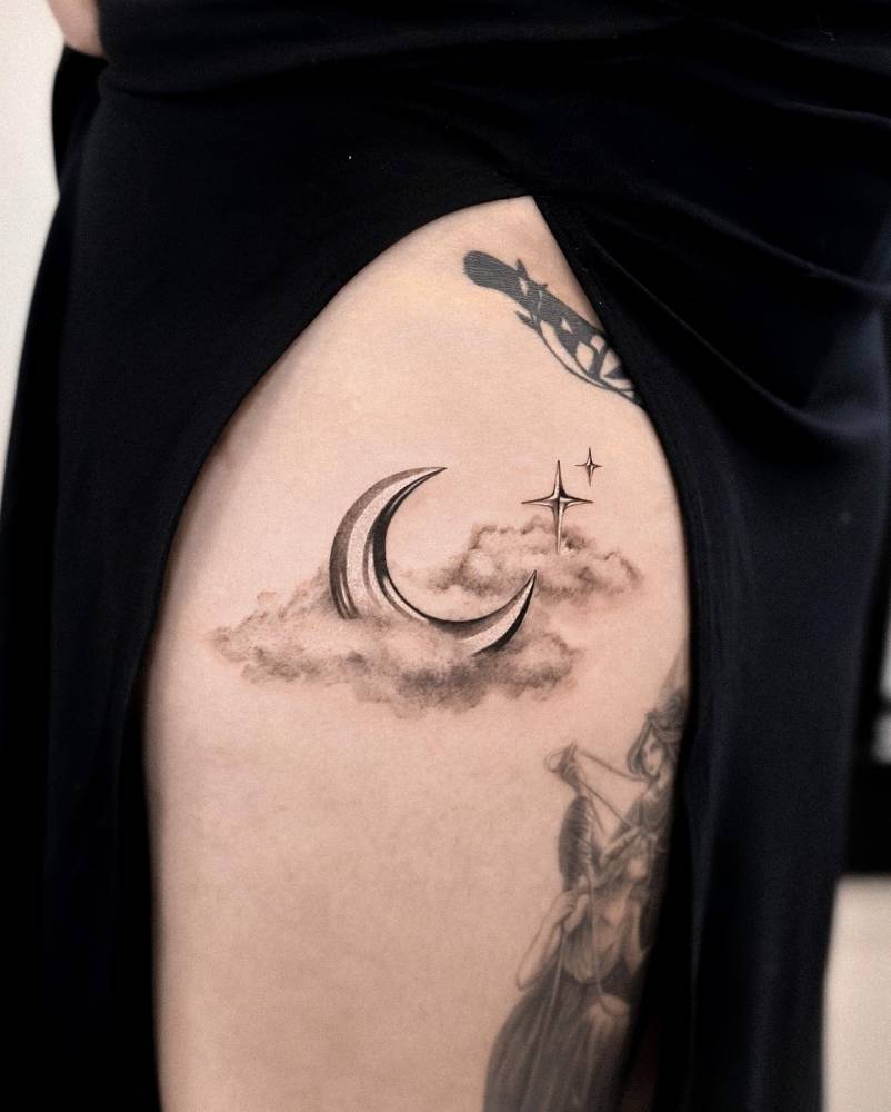 Chrome moon and clouds tattooed on the upper arm.