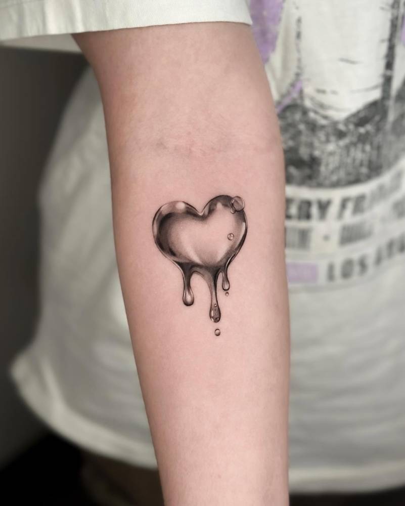 Water heart in micro-realism tattooed on the inner forearm.